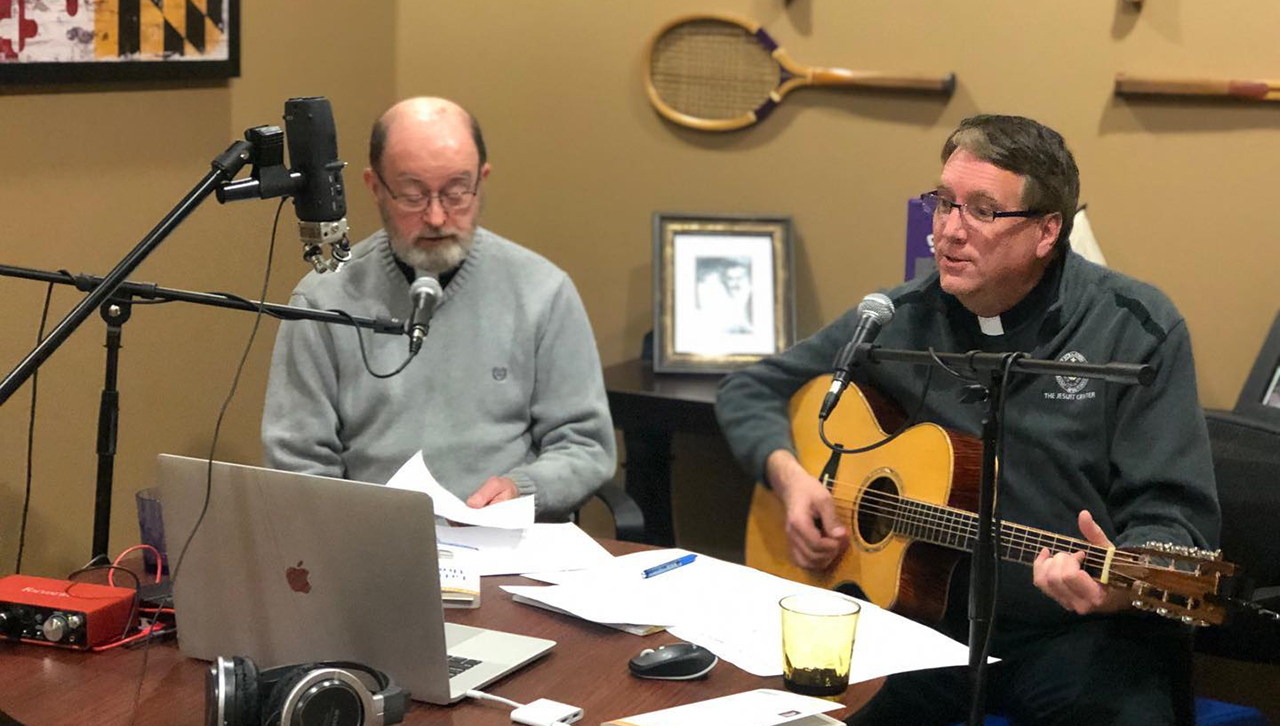 From left, the Rev. James D. Redington, S.J., and the Rev. Patrick Rogers, S.J., perform a song together while leading an Alumni Book Club discussion. 