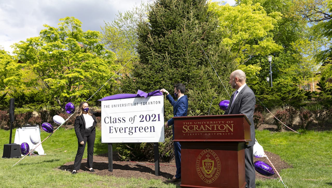 The University of Scranton dedicated a 26-foot Norway Spruce on the Dionne Campus Green as the Class of 2021 Evergreen at a ceremony on May 12. From left are: Adrianna O. Smith ’22, Student Government president, 2021-2022, a philosophy and theology double major and member of the Special Jesuit Liberal Arts Honors Program; Jeffrey M. Colucci Jr. ’21 Student Government president, 2020-2021, an accounting and finance double major; and Jeffrey P. Gingerich, Ph.D., acting president, provost and senior vice president for academic affairs.