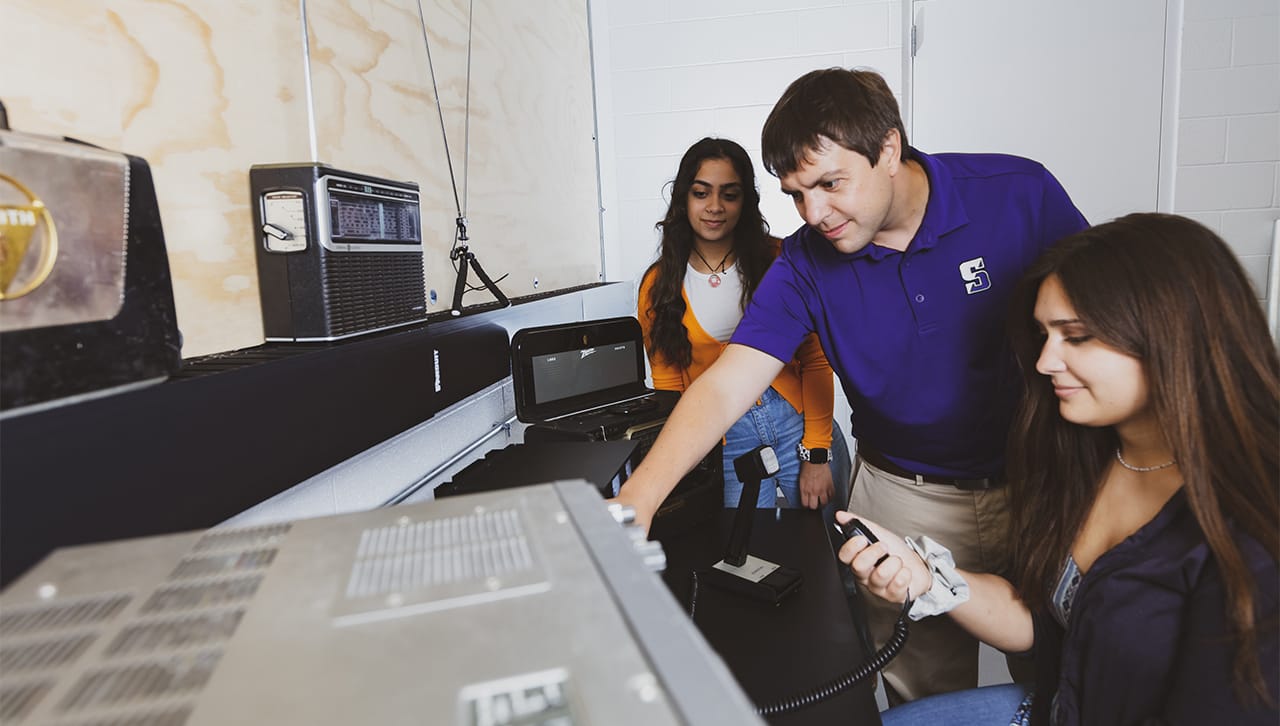 Nathaniel Frissell, Ph.D., assistant professor physics and electrical engineering at The University of Scranton, was awarded a National Science Foundation (NSF) grant of $49,995 to support the “The Ham Radio Science Citizen Investigation (HamSCI) 2022 Workshop,” which will take place March 18-19, 2022. Pictured working in the new ham radio station on campus, are, from left: Simal Sami, a sophomore who is part of Scranton’s Magis Honors Program in STEM; Dr. Frissell; and Veronica Romanek, a junior physics major.