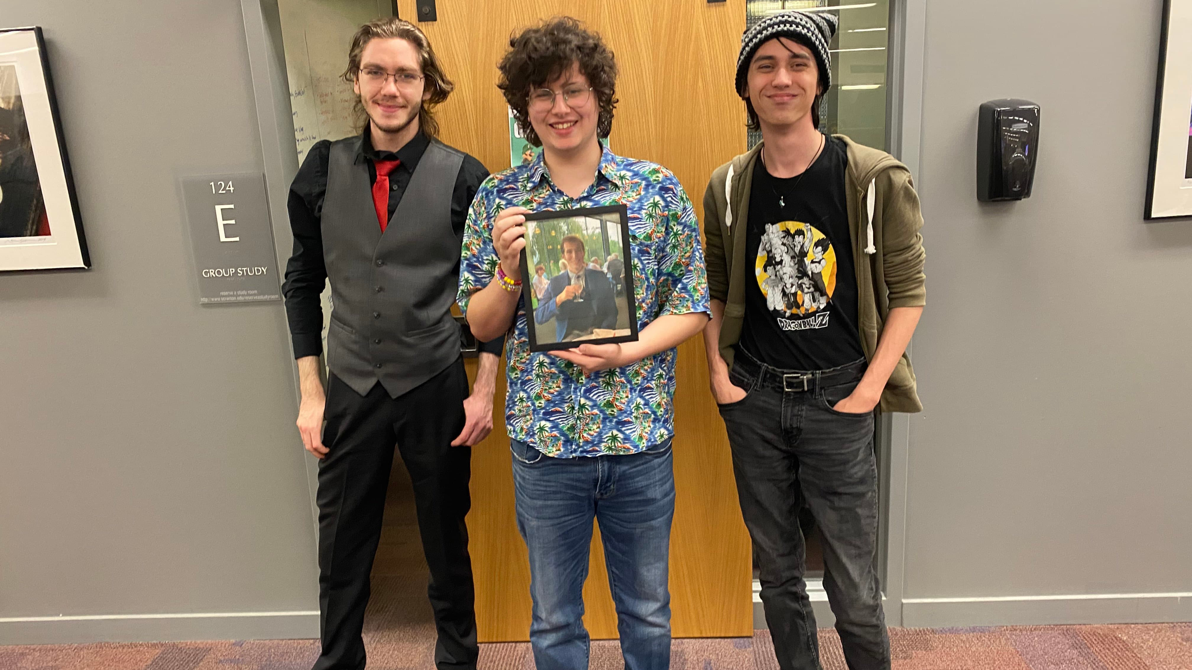 Winners of the Super Smash Brothers Tournaments, from left, are James B Davis IV, Caillou Kaneski, Terry Torres. In the framed photograph is Gaming Club Vice President Luke Capper. 