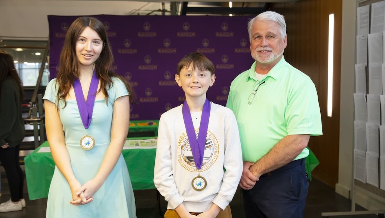 The University of Scranton announced medalists of its Earth Day Essay Contest for students in grades 5 to 12 at an Evening of Environmental Science event on campus in April. From left: Earth Day Essay Contest first place medalists Edie Hann, grade 9, Scranton Preparatory School; Colin Sickles, grade 5, St. Clare/St. Paul’s Elementary School; and Mark Murphy, director of the Office of Sustainability at the University.