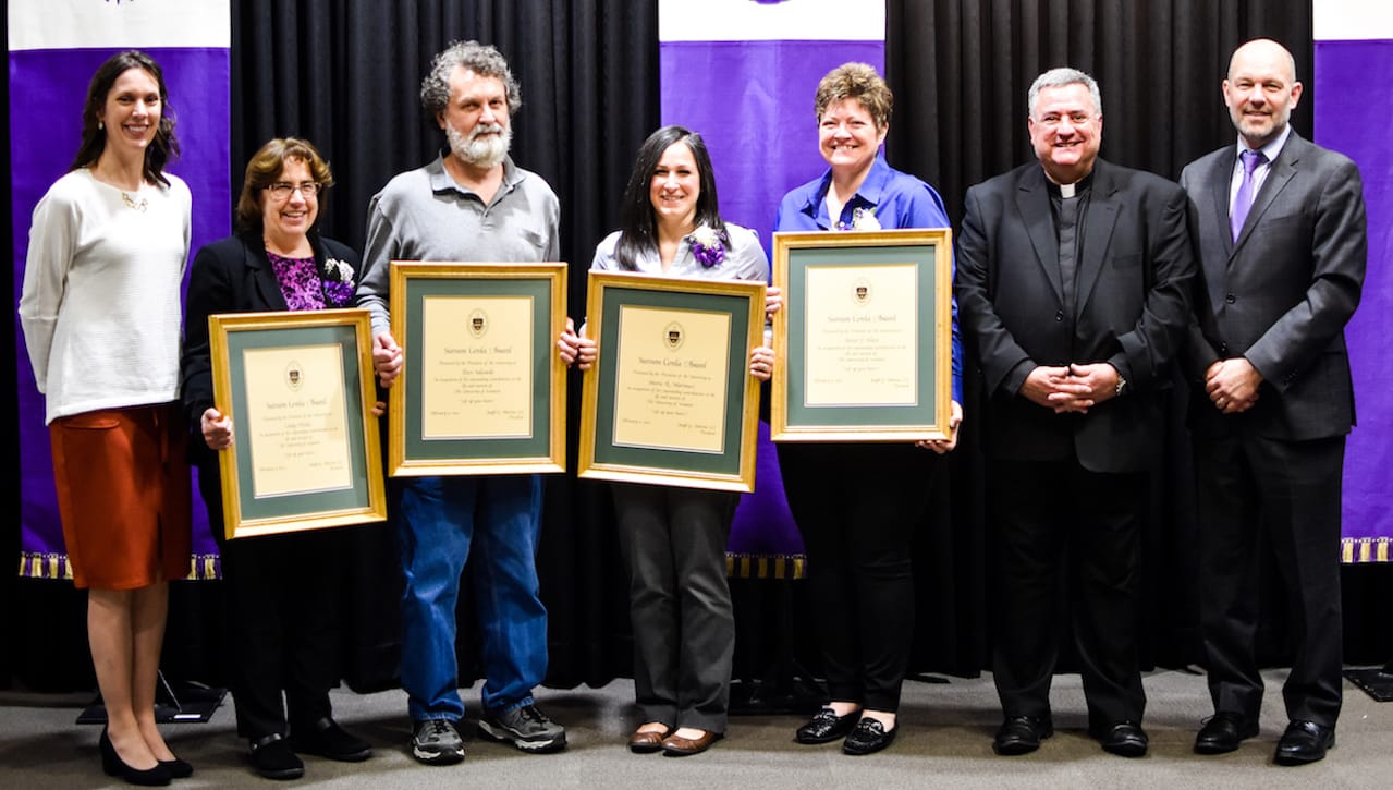 The 2021 Sursum Corda (Lift Up Your Hearts) Awards presented to four staff members at spring convocation, Apr. 5, 2022. From left, are: Patricia Tetreault, vice president for human resources; Sursum Corda Award recipients Cindy Hricko, business applications analyst and manager of enterprise application for Information Technology; Pete Sakowski, network resources technician; Maria Marinucci, director of the Cross Cultural Centers; Kristi Klien, administrative assistant for the Center for Career Development; and Rev. Joseph Marina, S.J., president; and Jeff Gingerich, Ph.D., former provost and senior vice president for academic affairs.