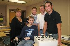 A team of University of Scranton engineering students and faculty from the Physics/Electrical Engineering  Department successfully reconfigured an XBOX to meet the physical capabilities of Danny Sampson, a 15-year-old boy who suffered a spinal cord injury.  Presenting the reconfigured XBOX to Danny (front) are, from left, Christine Zakzewski, Ph.D., associate professor and chair of physics and electrical engineering, University of Scranton engineering students Patrick Wagner, Raymond Orchard and Ryan Savage. The project was supported by a grant from the Northeast Pennsylvania Technology Institute.