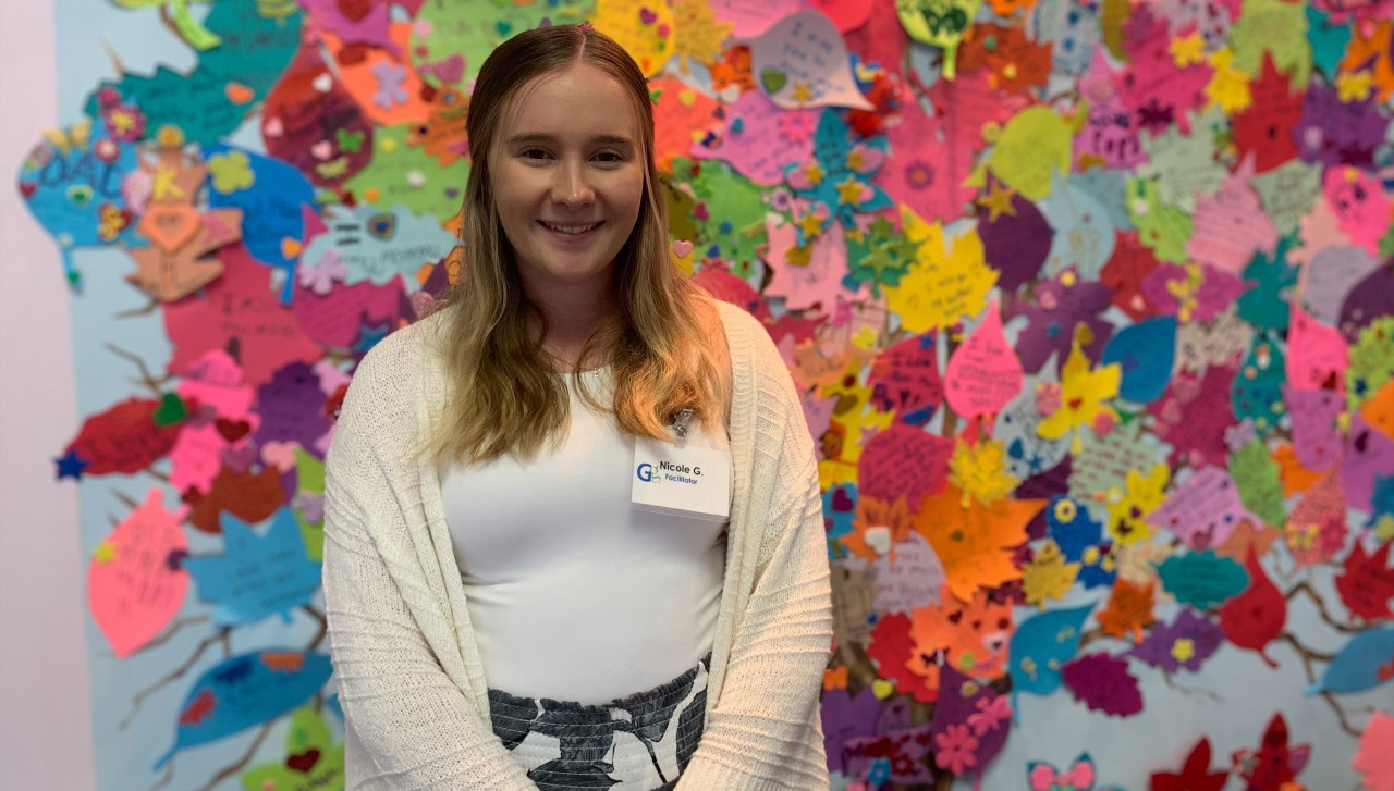 Portrait of Nicole Gomber, a woman with long blond hair dressed in a cream sweater and jeans. She is a University of Scranton student who completed an internship at a grief support center.