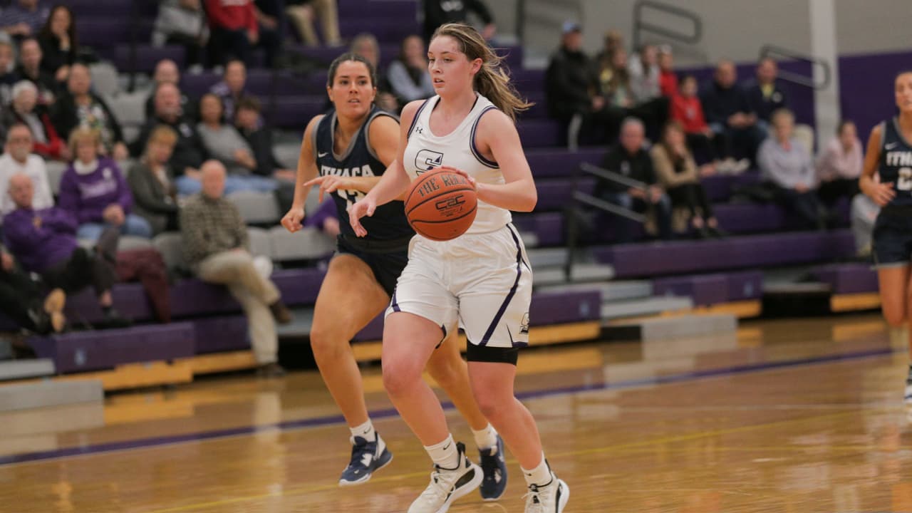 Two women playing basketball. University of Scranton player dribbling ahead.