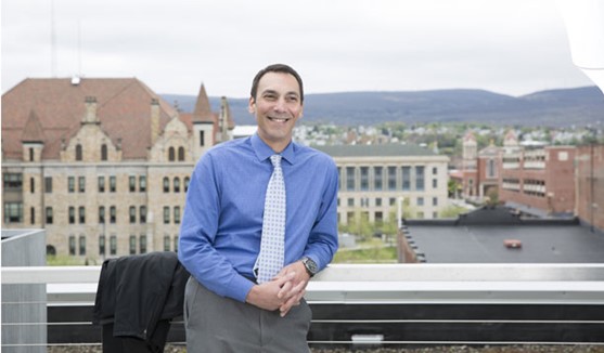Dr. Paul Datti standing on balcony with blue sky in background