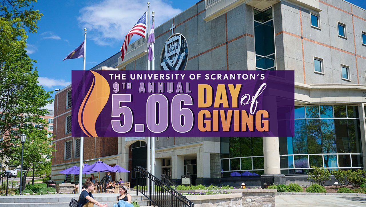 A graphic stating "5.06: The University of Scranton's Ninth Annual Day of Giving" superimposed over an image of two students sitting at the Flagpole Terrace at The University of Scranton.