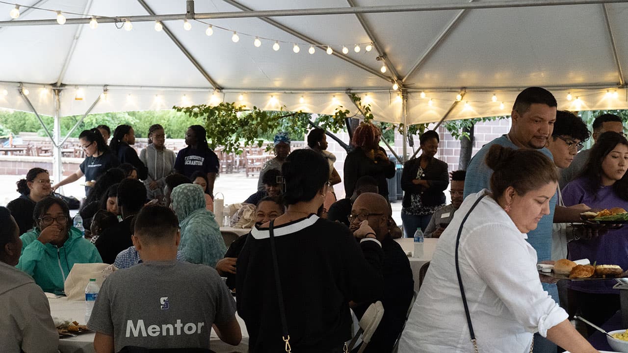 People dining at tables located under a white tent 