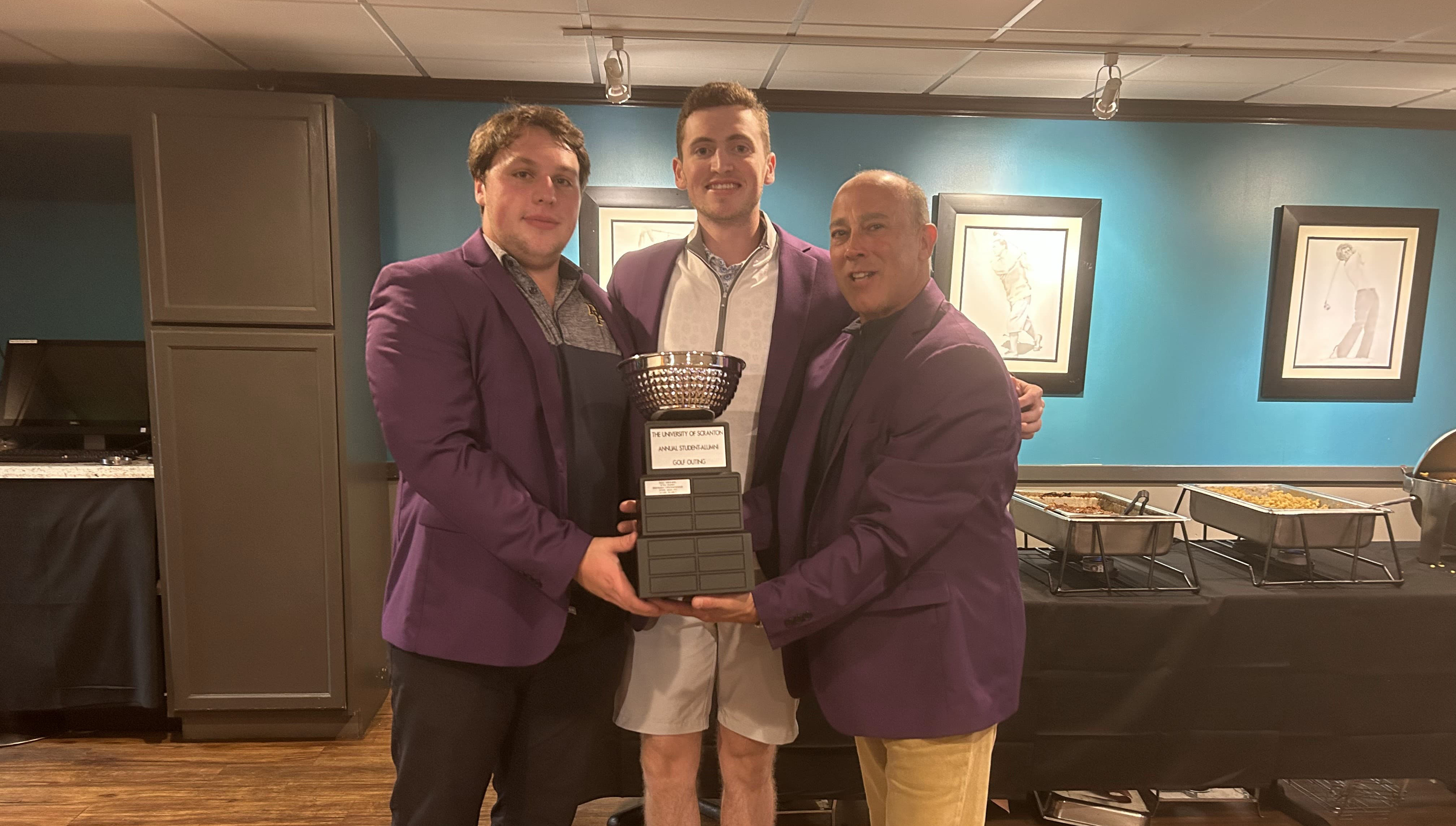 From left, Alex Kenneson ’24, Liam Dunfee ’24 and Al Guari ’88 enjoy a moment together after winning the 2023 Alumni-Student Golf outing. Kevin Gremse '87, not pictured, also won the tournament.
