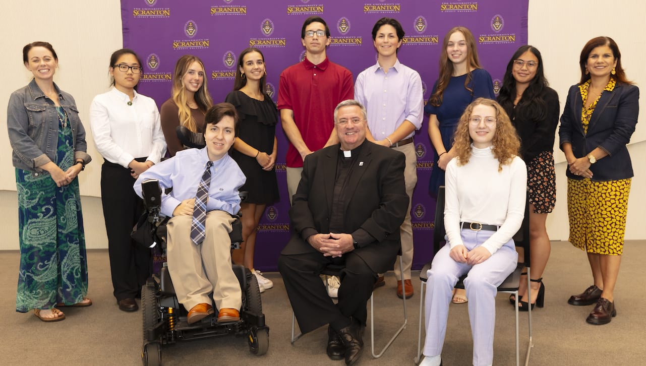 Nine students from The University of Scranton’s class of 2027 have been awarded four-year, full-tuition Presidential Scholarships. Seated, from left, are: Presidential Scholar Matthew Rakauskas; Rev. Joseph Marina, S.J., president of The University of Scranton; and Presidential Scholar Caitlin Wilson. Standing are: Sarah Kenehan, Ph.D., executive director of the University’s Gail and Francis Slattery Center for Ignatian Humanities; Presidential Scholars Tiffany He, Olivia Ulrich, Maria Vyzaniaris, Brian Repsher Jr., Andrew Mauriell, Jillian DelBalso and Jessieca Aguasin; and Michelle Maldonado, Ph.D., provost and senior vice president of academic affairs.