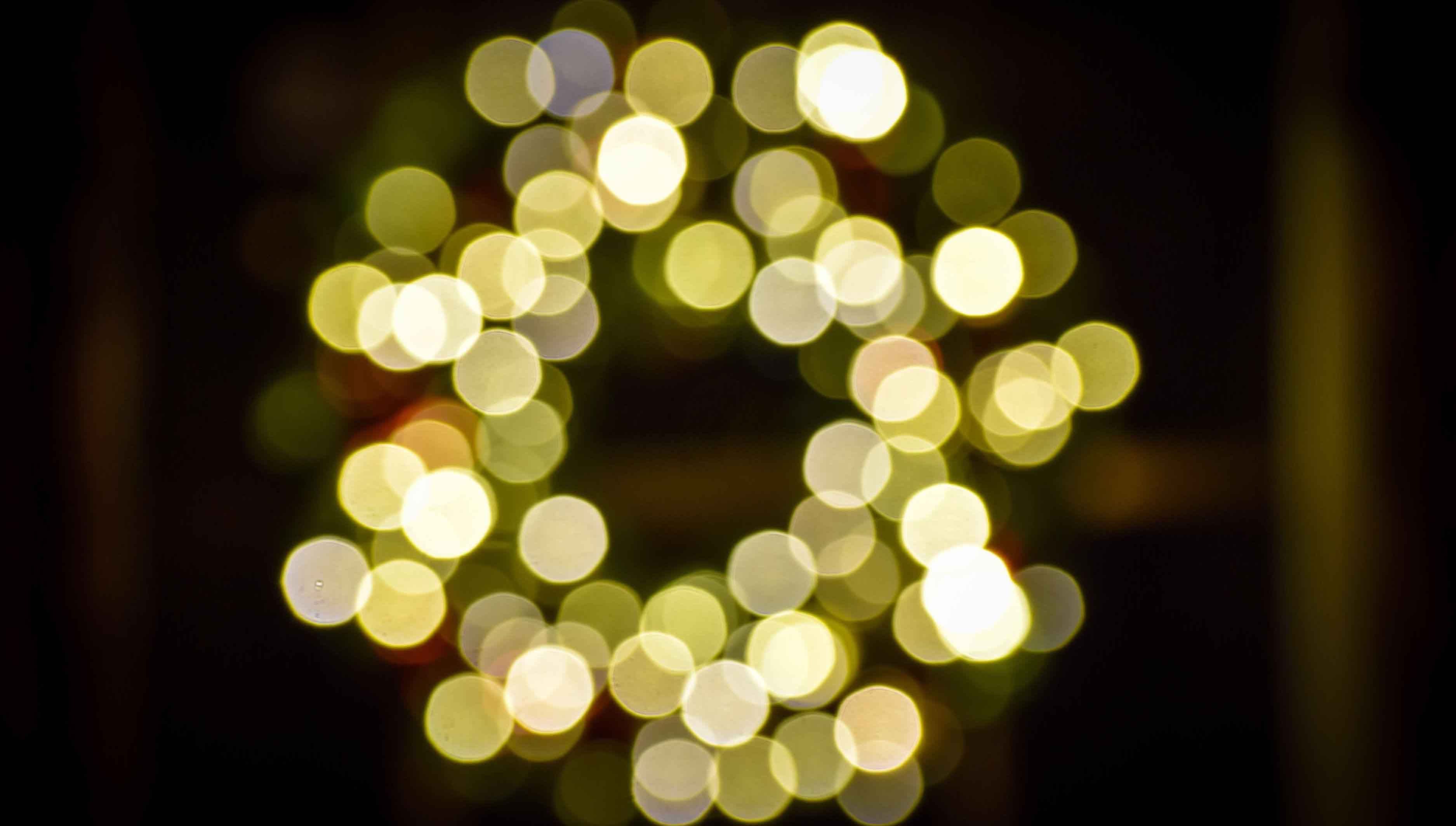 An out-of-focus Christmas wreath adorned with lights.
