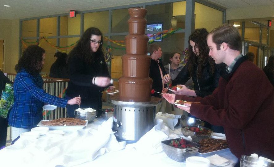 chocolate fountain in DeNaples Center with tables of items for dipping and University community members partaking