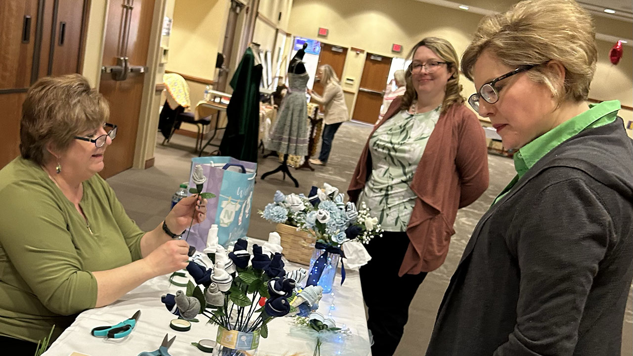 Rose Termini, a crafter since 1991, demonstrated the process she uses to create rosebud displays from baby clothing. Shown is the crowd gathered at her booth during the first University of Scranton Staff Showcase on March 13.