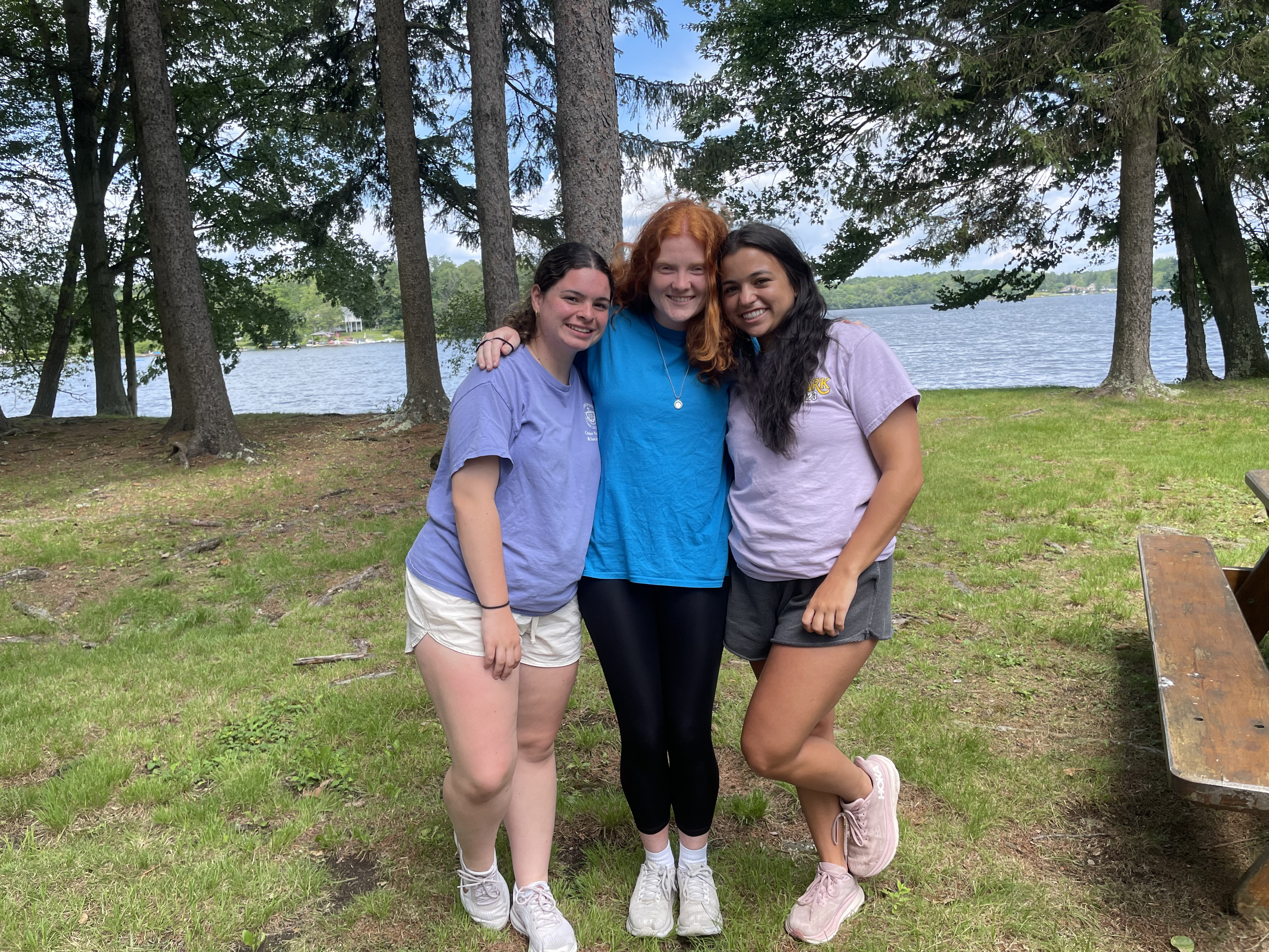 Abby Casal, Laura Echausse, and Sophia Pisarski hugging in a forest