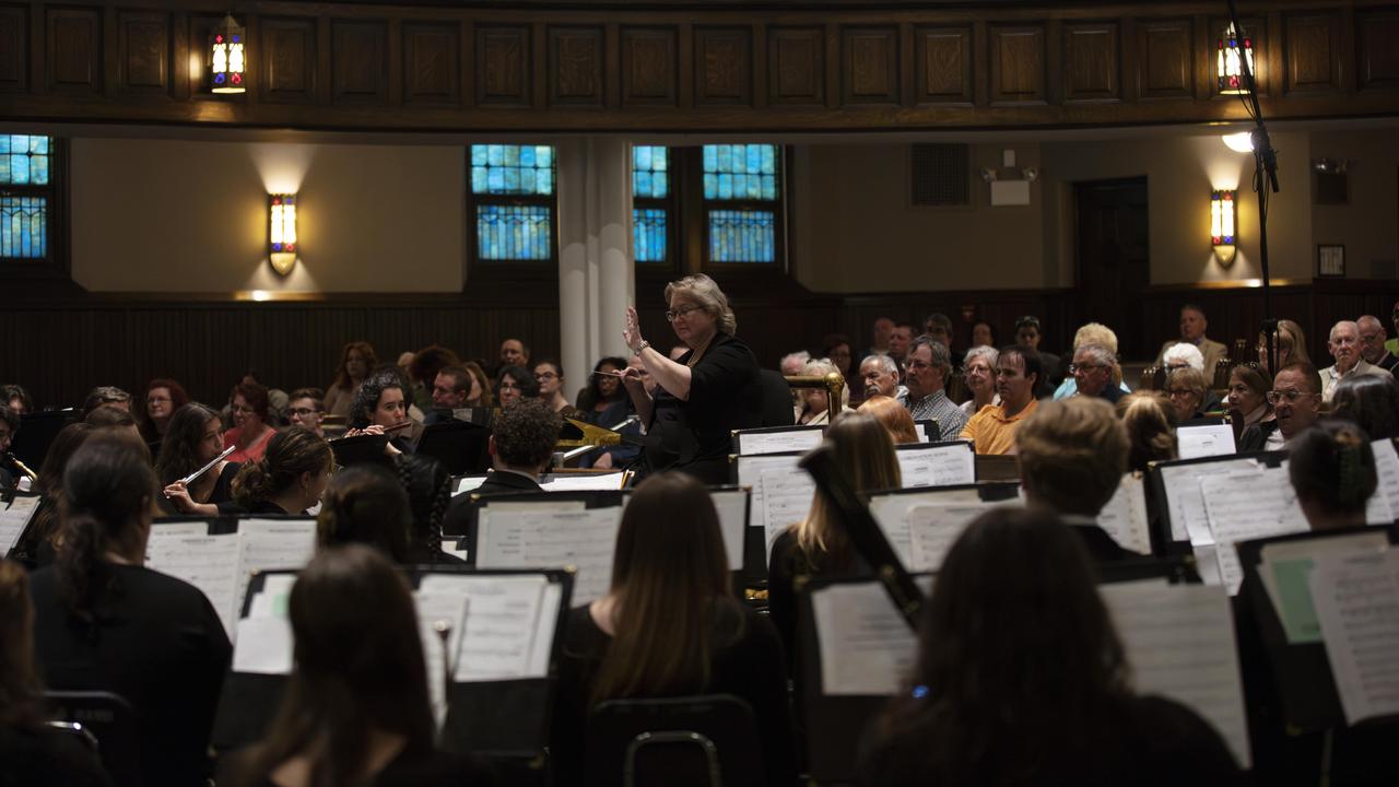 A conductor leads student musicians at a recital