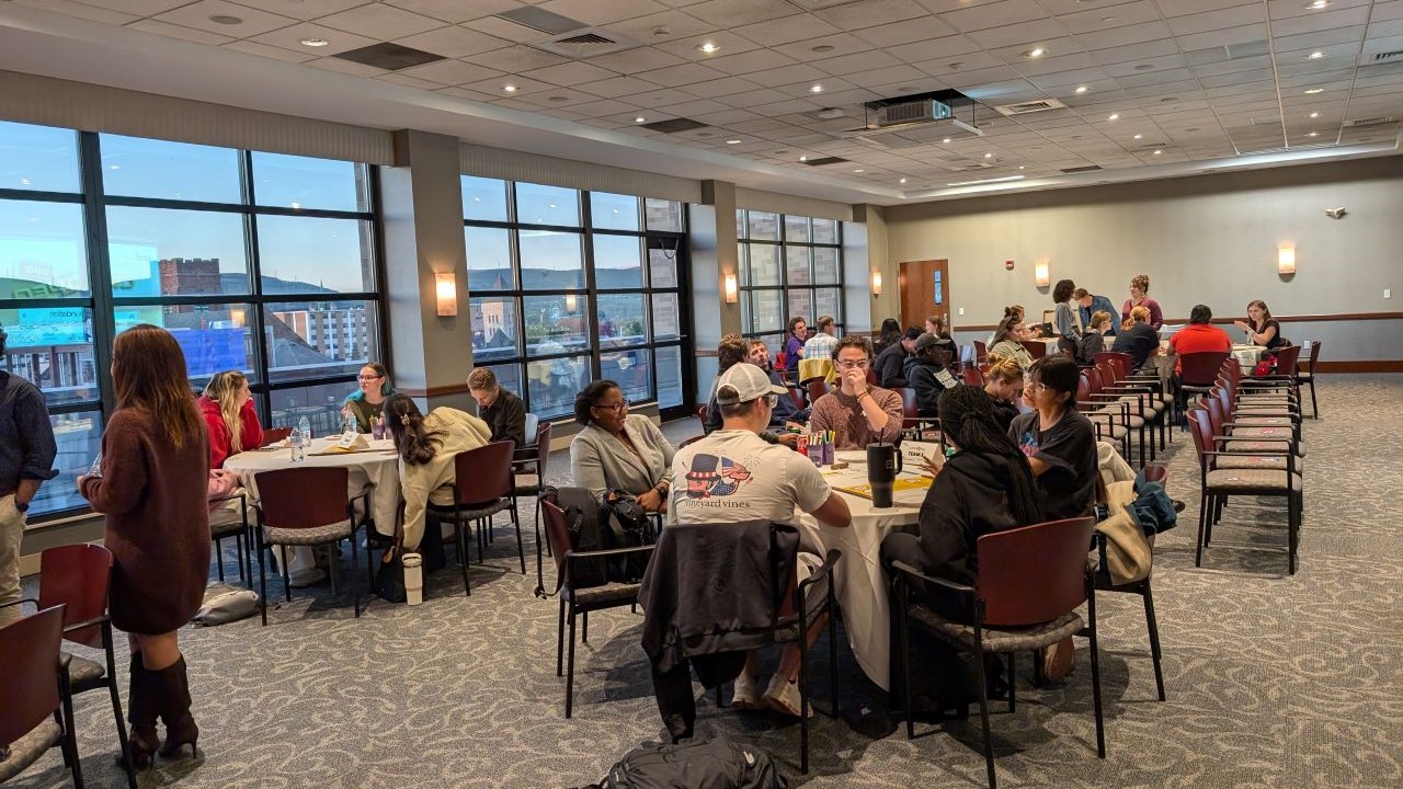 Students seated at tables and rows of chairs in event space