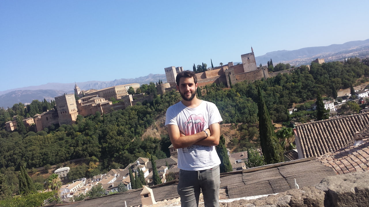 Fabian Bizcocho standing front of blue sky and several castle buildings in Spain