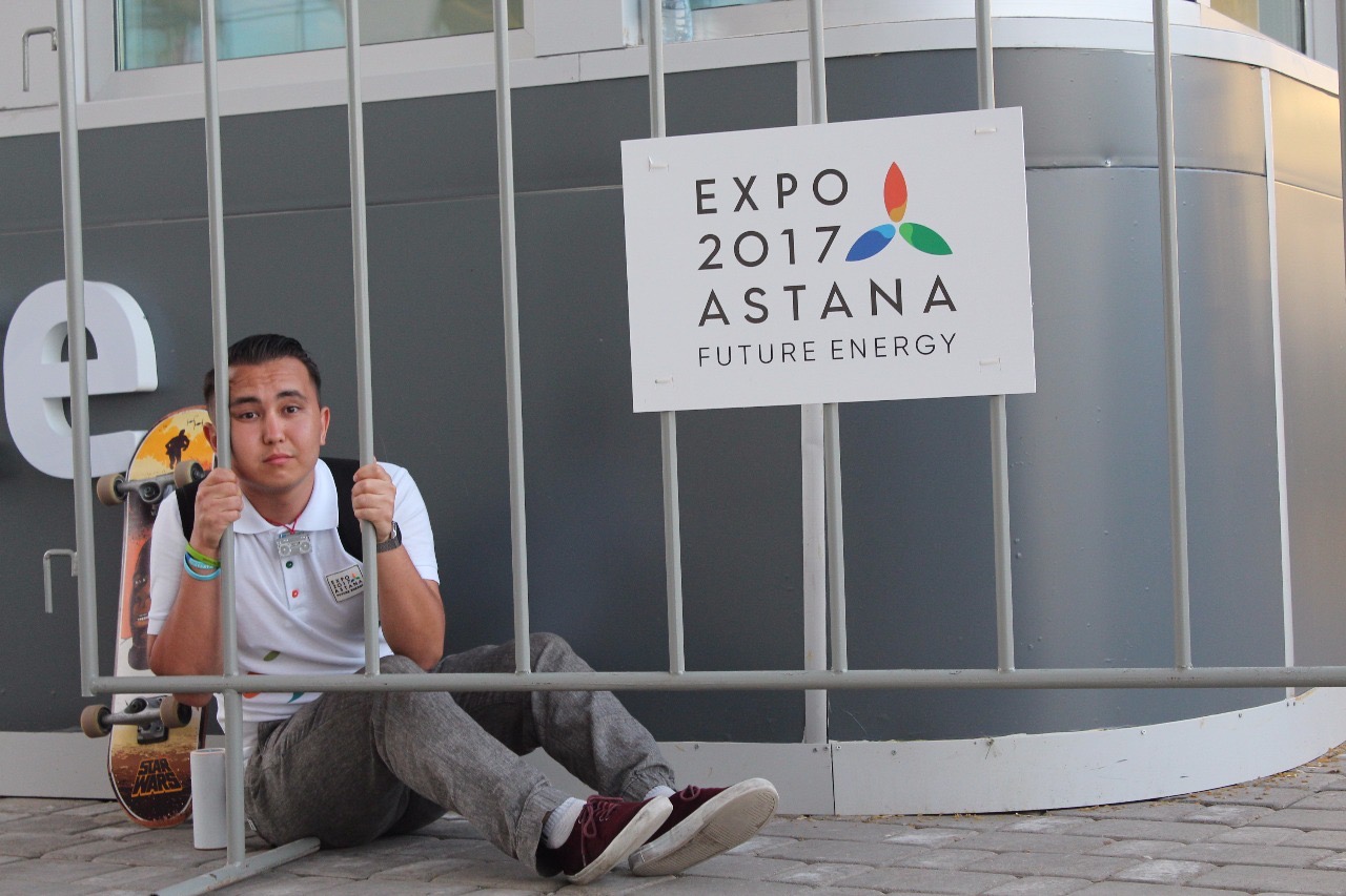 oung male with white t-shirt playfully sitting behind metal bars