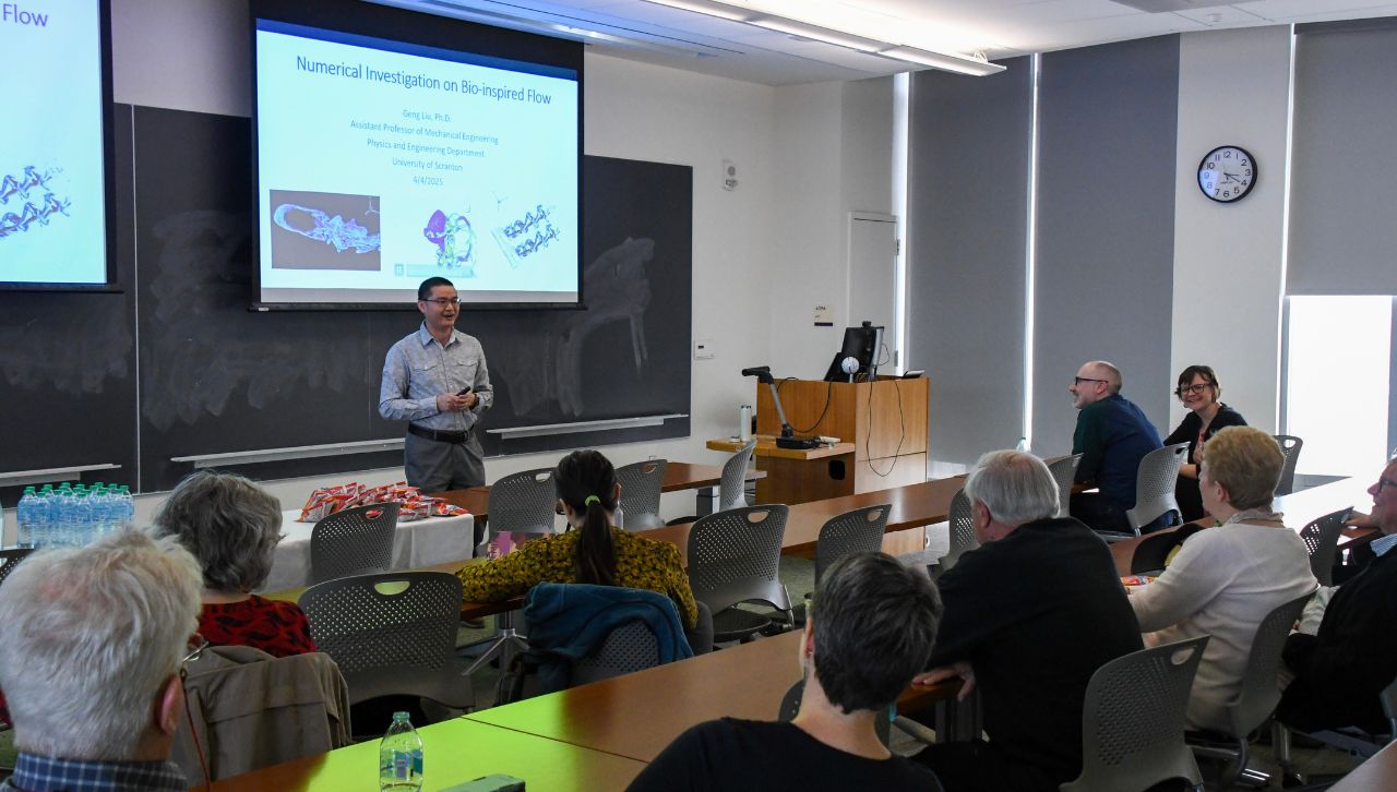 a professor smiles during a lecture to fellow professors