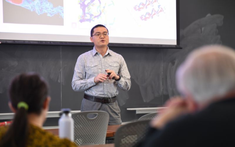 a professor, standing, explains to a seated audience