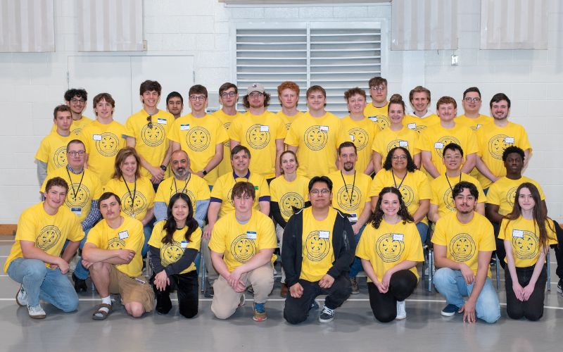 Group photo of participants wearing yellow shirts, gathered together for a team event or workshop.