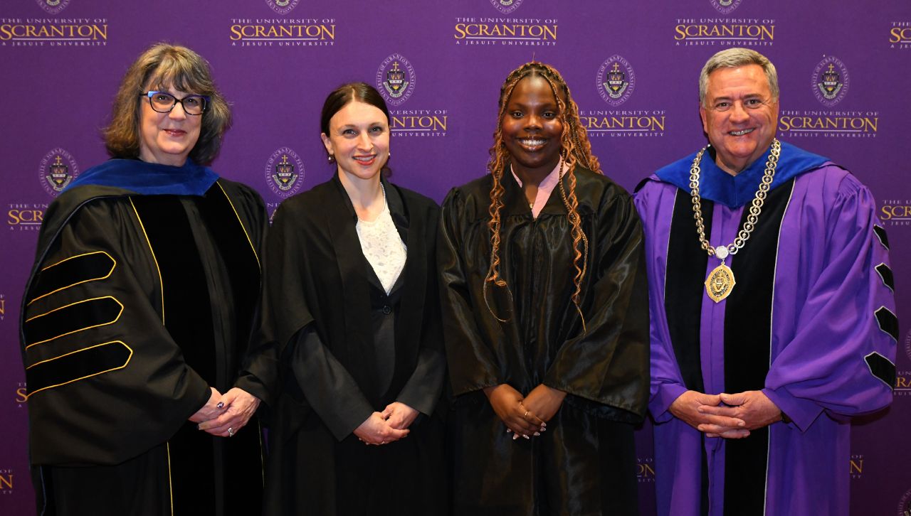 Graduates and faculty members pose together at a graduation ceremony at the University of Scranton.