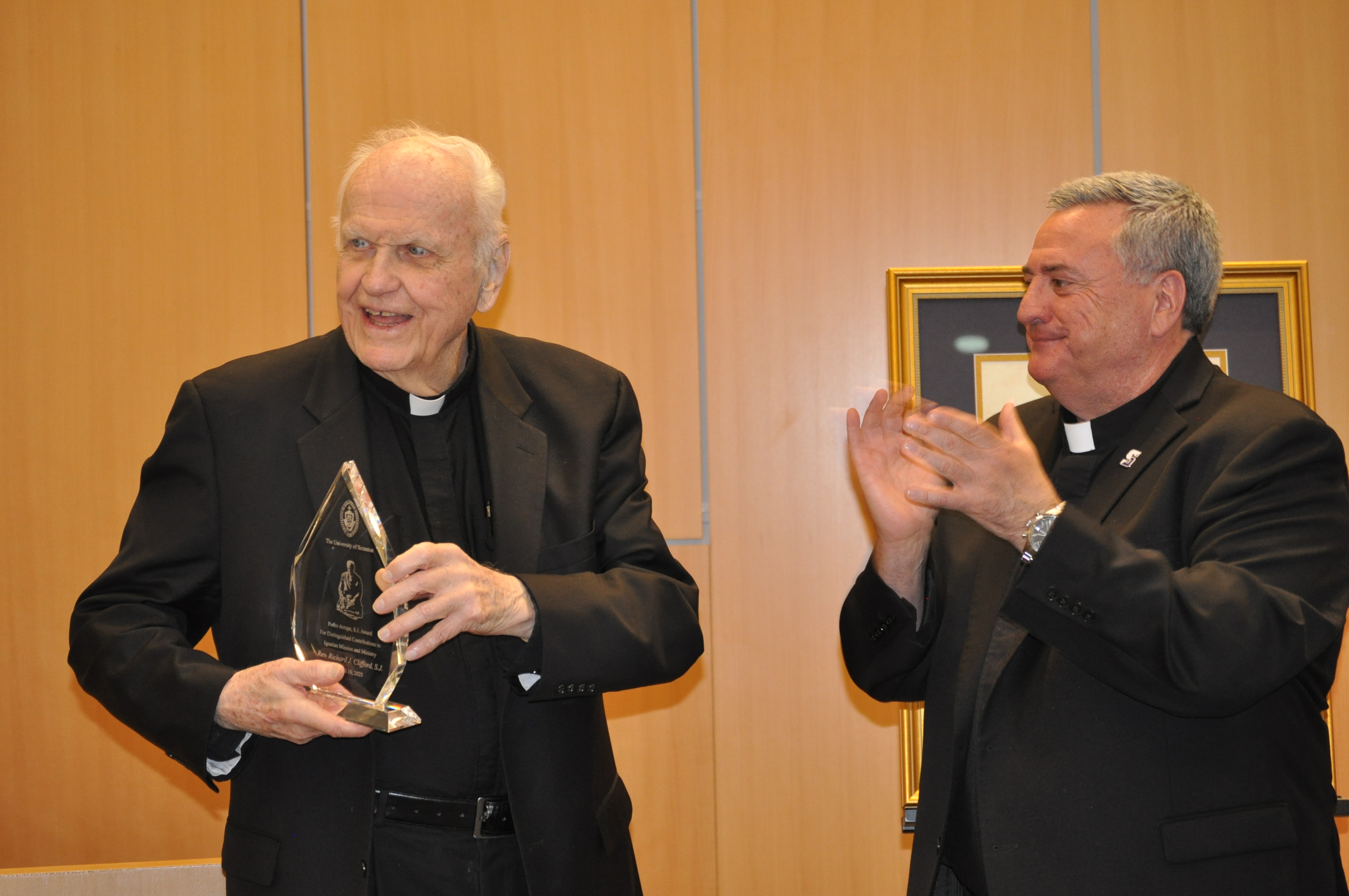 an individual claps as another individual holds an award