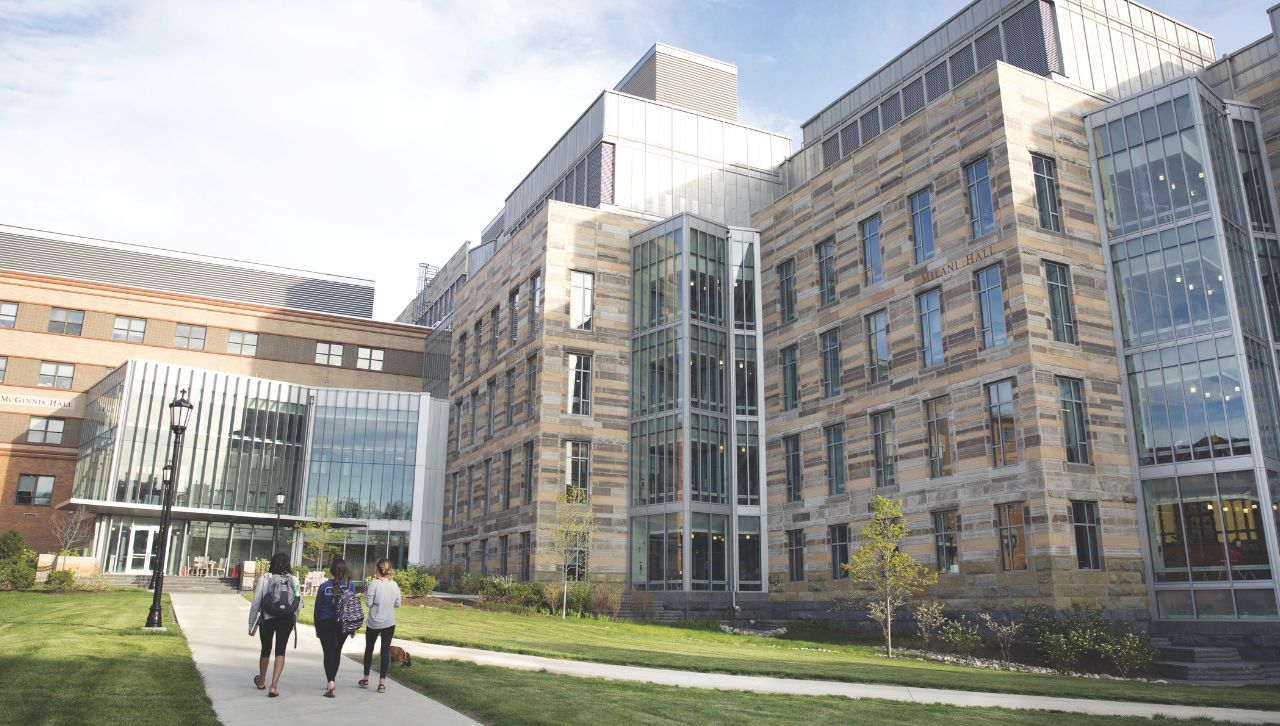 an outdoor scene of the loyola science center with a few individuals walking on the sidewalk next to the building