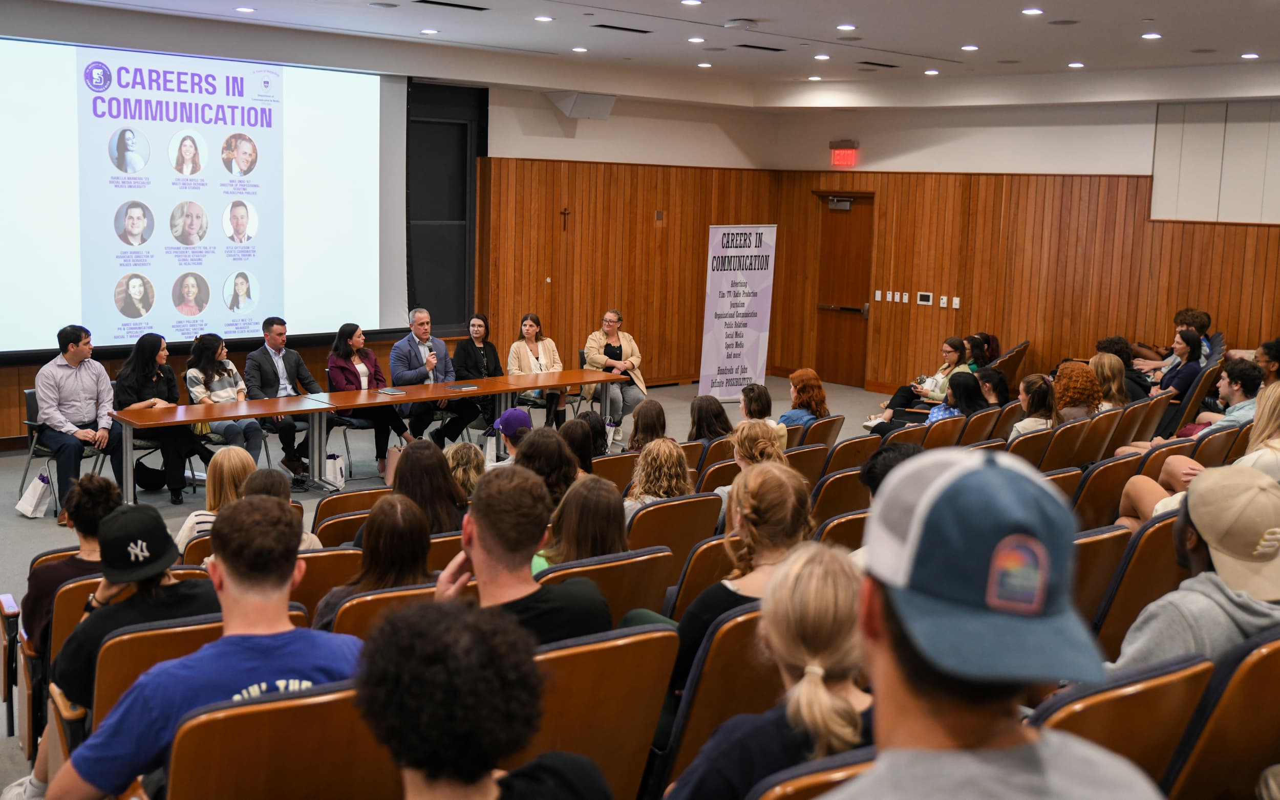 Panel discussion on careers in communication featuring various speakers at a university event, with an audience engaged in the session.