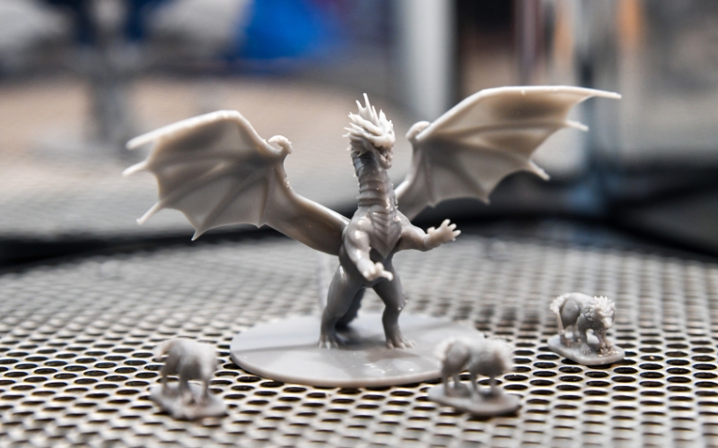 A detailed gray plastic dragon miniature standing with its wings spread, accompanied by smaller animal figures.