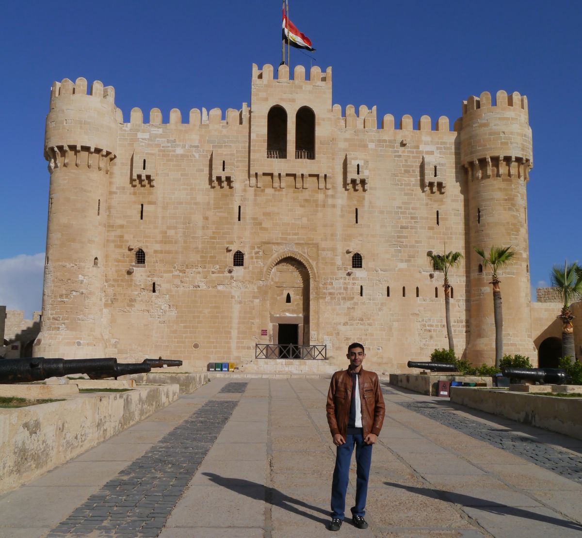 young male in front of large buildings with cannons