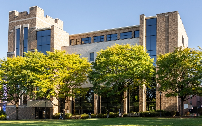 Modern building with large windows surrounded by green trees.