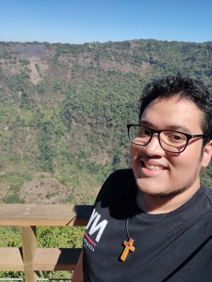 male student with dark hair stands at the edge of a volcano basin.