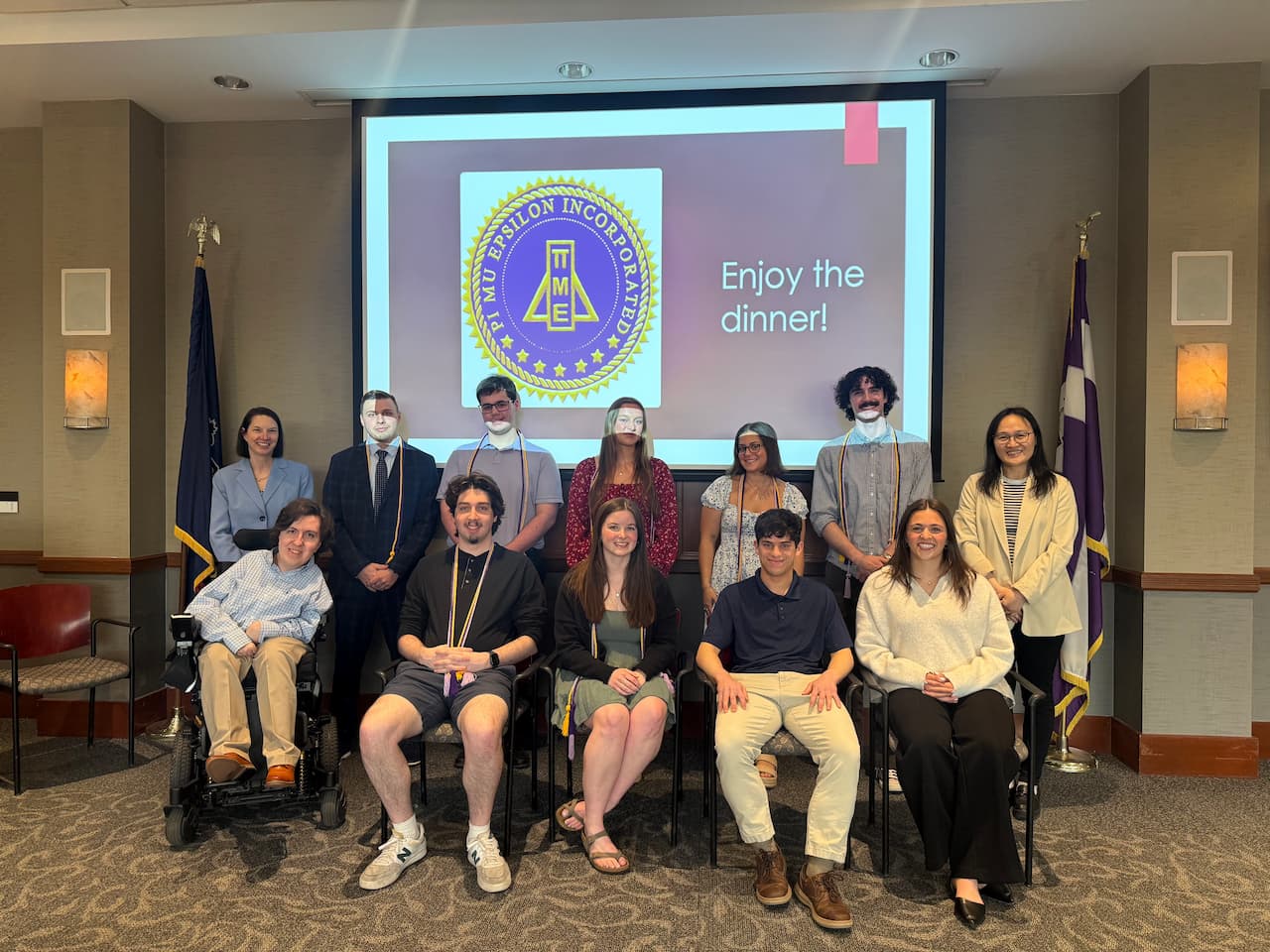 Two rows of young adults in front of a banner featuring the math association icon.